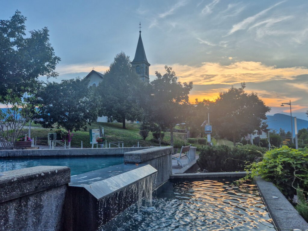 Église et fontaine du centre-bourg de Mouxy au coucher du soleil